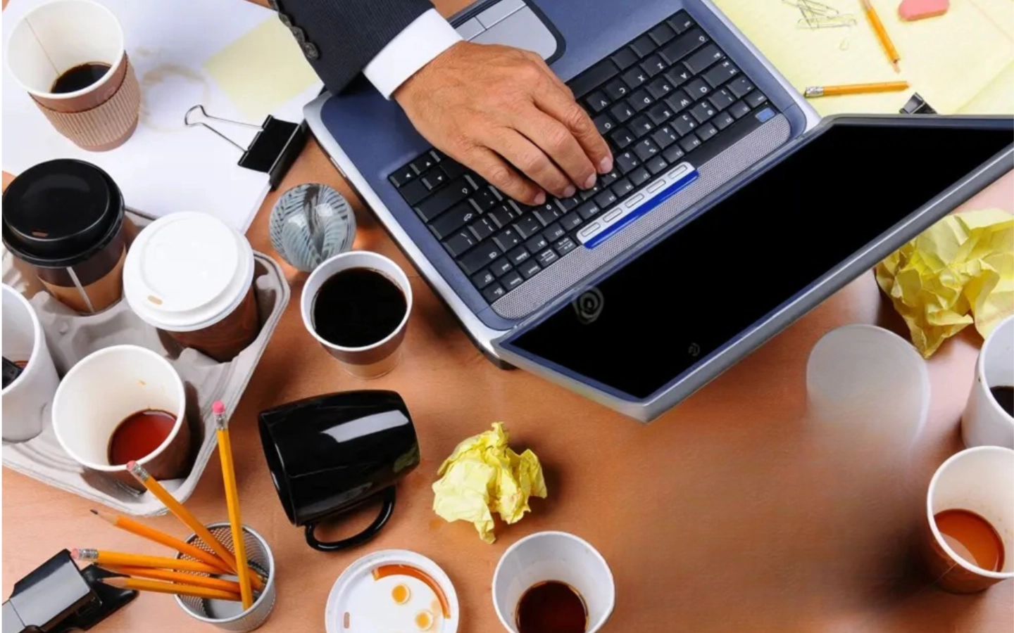 Start here 1 A slightly messy desk with a laptop coffee cup, and notebook